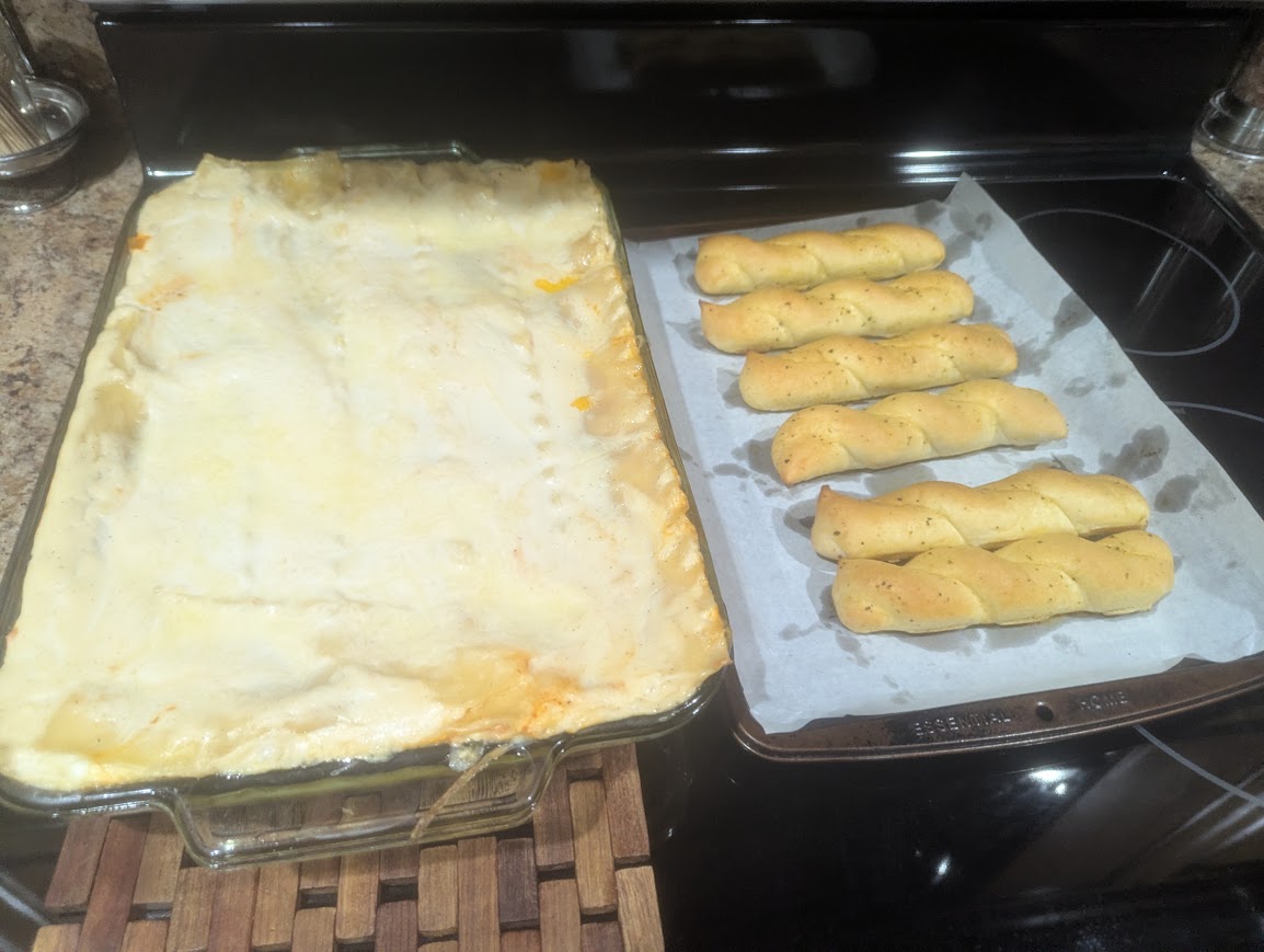 Our baked two-sauce lasagna in a glass dish with breadsticks alongside
